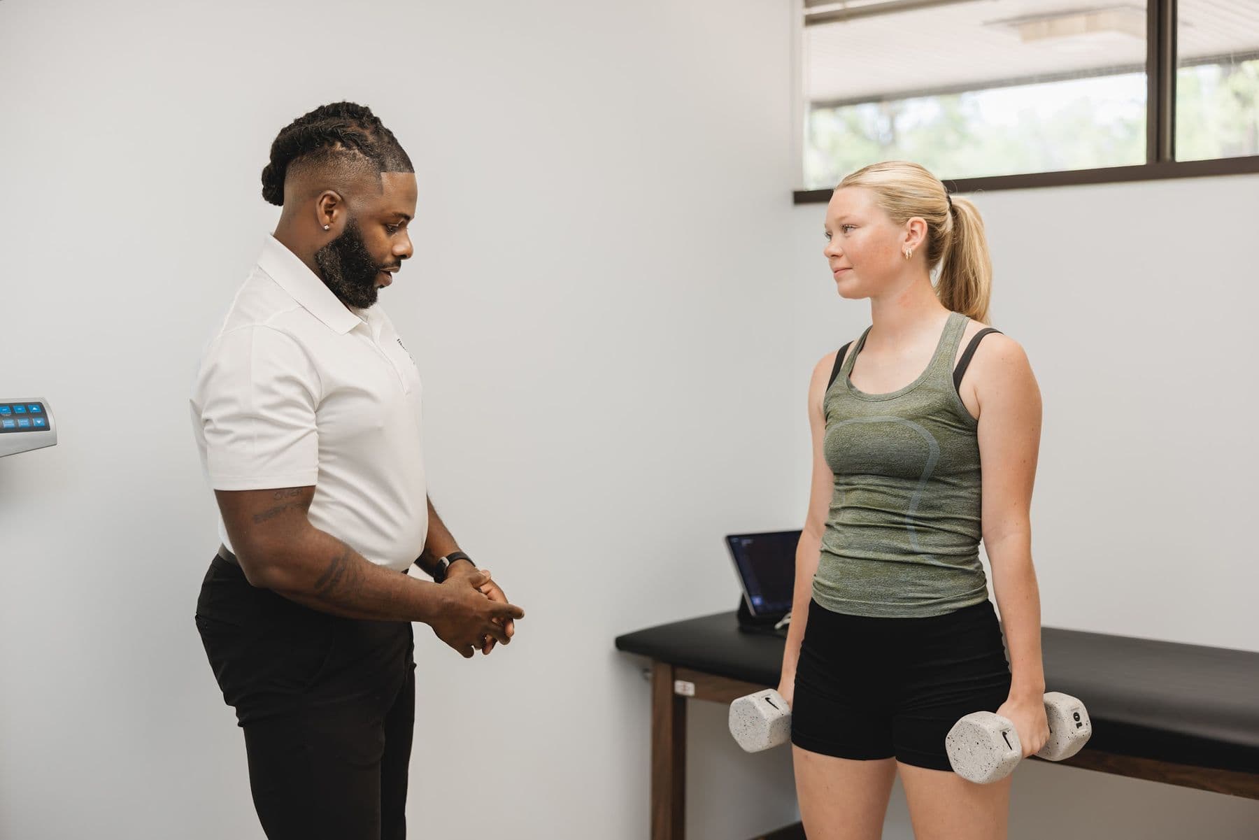 A Chiron physician working with an adult member holding dumbbells