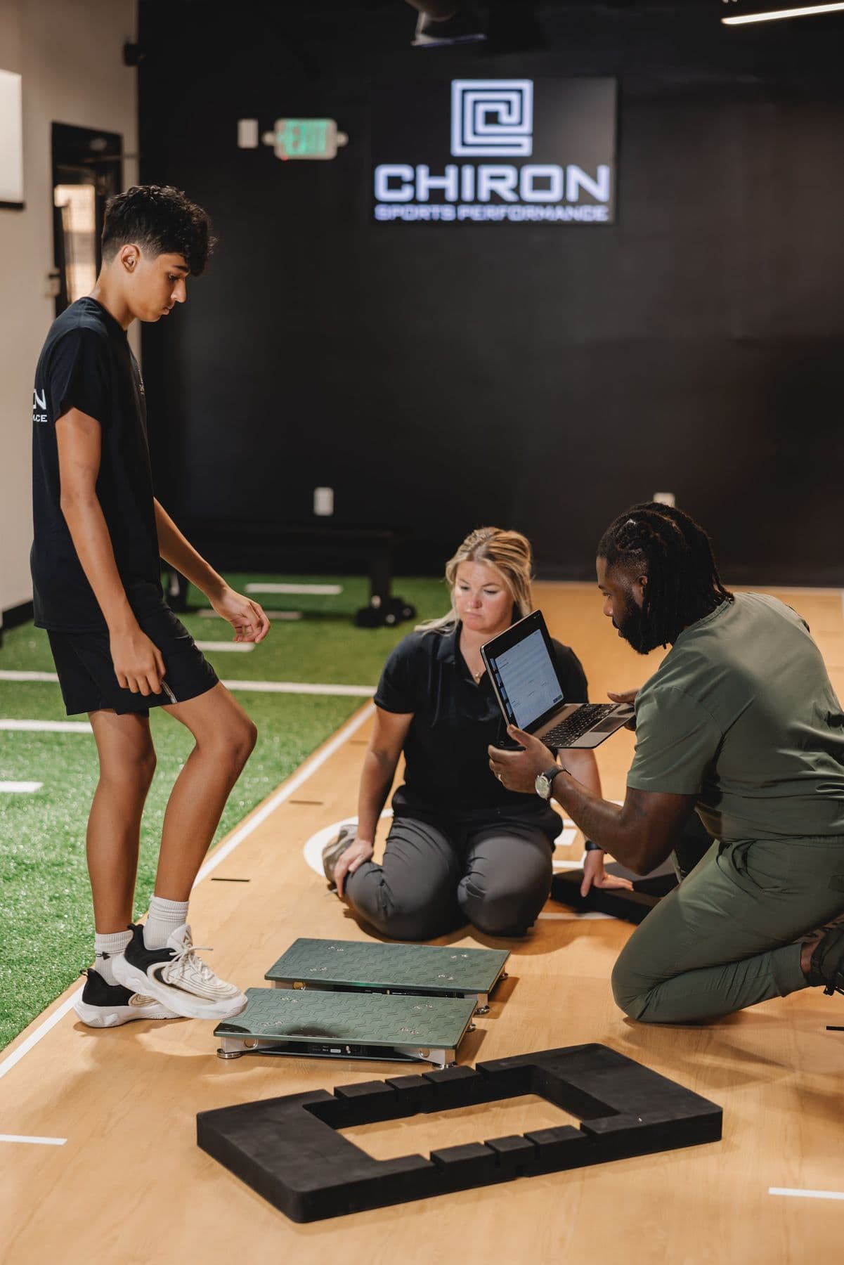 Chiron coaches recording an athlete's jump test on a tablet